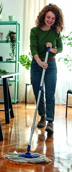 Une femme passe la serpillière dans un intérieur lumineux et végétalisé.
